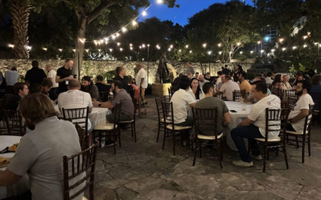 Dozens of people from the Emergent Software team are dining at a large outdoor venue. 