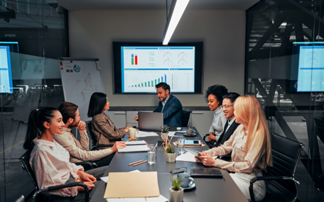 Business professionals in a conference room reviewing the client's increased value after launching their new custom software. 