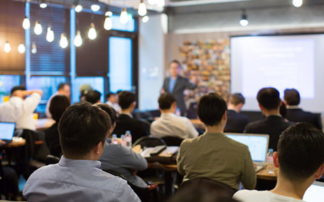Person is lecturing a room full of business professionals.